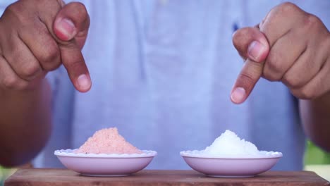 Forefinger-showing-Pink-himalayan-salt-and-white-crystal-salt-on-the-white-small-bowl