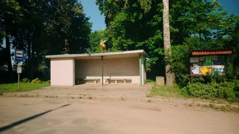 Eine-Bushaltestelle-Aus-Backstein-In-Einem-Lettischen-Dorf,-Mit-Einer-Tafel-Mit-Gemeindemitteilungen,-Vor-Dem-Hintergrund-Einer-üppigen-Sommerlandschaft