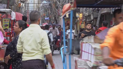 Traditional-Indian-rickshaws-and-e-rickshaws-on-the-narrow-lanes-of-Chandni-Chowk,-chaotic-cables-and-wires-hanging-on-poles-in-background