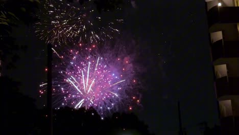 Colorful-fireworks-light-up-the-night-sky-next-to-a-tall-building-during-a-festive-celebration