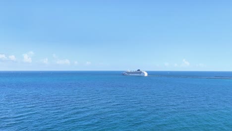 A-drone-captures-a-cruise-ship-departing-Miami-Port-into-the-Atlantic-Ocean,-showing-the-ship-sailing-in-the-clear-blue-sea