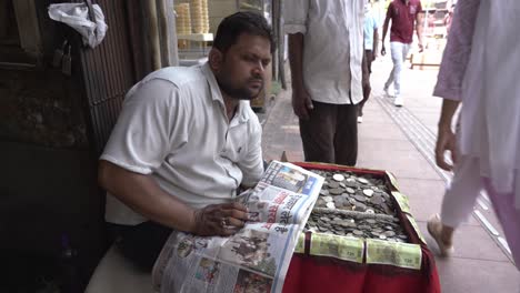 Perfil-Lateral-De-Un-Hombre-Asiático-De-Mediana-Edad-Leyendo-Un-Periódico-Hindi,-Antiguo-Cambista-De-Moneda-De-Delhi