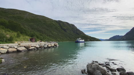 Boat-transporting-a-people-over-a-green-lake-to-begin-a-hiking-trek-in-the-Norwegian-mountains