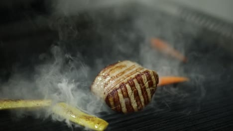 Un-Jefe-Cocina-Comida-En-Una-Parrilla-Y-Le-Agrega-Verduras.-Primer-Plano,-Plano-Insertado.