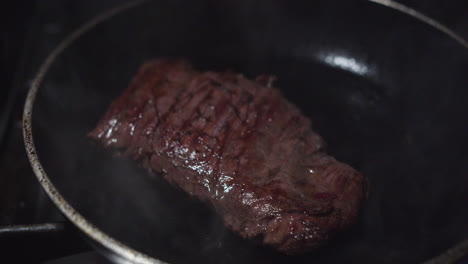 Nice-slow-motion-detail-shot-of-a-beef-tenderloin-heating-up-and-smoking-in-a-hot,-oiled-frying-pan-inside-an-industrial-kitchen-of-a-Mexican-restaurant