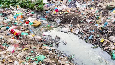 Water-stream-passes-through-contaminated-area-with-trash-and-plastic-waste-posing-a-health-risk-with-disease-and-chemicals