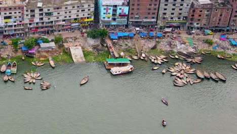 Aerial-view-on-wooden-passenger-boats-at-port-of-Buriganga-river-in-Dhaka,-people-walking-on-the-streets