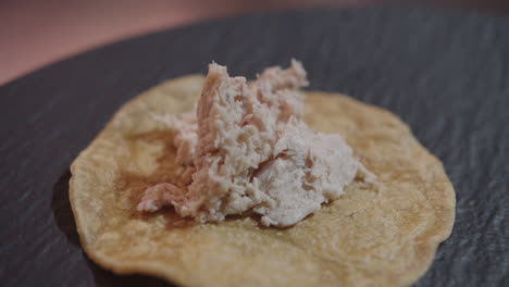 Amazing-slow-motion,-close-up-shot-of-chicken-being-spooned-into-a-Mexican-tortilla-by-a-professional-chef-to-prepare-enchiladas-in-green-sauce