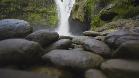 Beautiful-waterfall-in-Bali-surrounded-by-lush-greenery-and-rocky-terrain