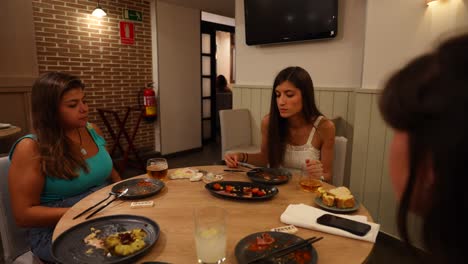 Tres-Mujeres-Conversando-Y-Compartiendo-Una-Comida-En-Un-Acogedor-Restaurante.