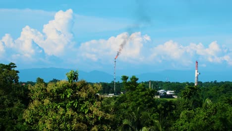 Contaminación-Ambiental-A-Través-De-Campos-De-Gas,-Montañas-Y-Grandes-Nubes-En-El-Fondo-Con-Un-Cielo-Azul-Y-Un-Bosque-Verde-Alrededor,-Toma-Estática-Con-Espacio-De-Copia