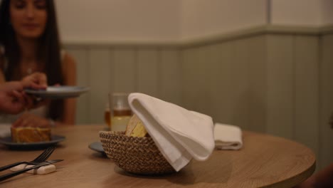 Female-hand-with-tongs-taking-slice-of-bread-from-basket-and-placing-on-plate