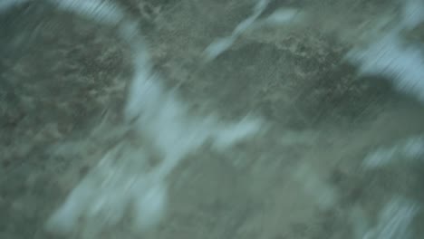 Extreme-closeup-shot-of-sea-waves-coming-to-coastline-and-depositing-sand