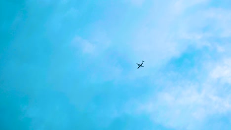 Avión-Volando-En-El-Cielo-Azul-Con-Algunas-Nubes-Pequeñas-En-Un-Día-Soleado,-Cámara-Lenta-Y-Espacio-De-Copia