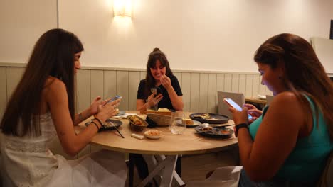 Tres-Amigos-Usando-Sus-Teléfonos-En-Un-Acogedor-Restaurante-Después-De-Cenar.