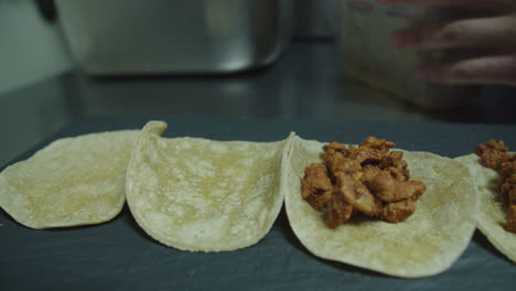 Nice-slow-motion-detail-shot-of-a-chef-placing-“cochinita”-meat-to-prepare-Mexican-tacos-to-order-at-a-Mexican-restaurant-in-his-industrial-kitchen