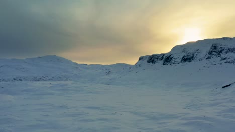 Yellow-glow-from-setting-sun-above-ridgeline-casts-light-across-clouds-in-Haukelifjell-mountain-pass-in-Vinje-Telemark-Norway-at-sunset