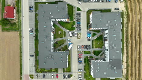 op-down-view-of-a-modern-residential-complex-with-a-well-organized-parking-area-and-surrounding-greenery,-emphasizing-urban-living-and-community-layout