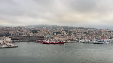 aerial-drone-fly-above-Genoa,-Italy-port-and-cityscape-during-cloudy-day