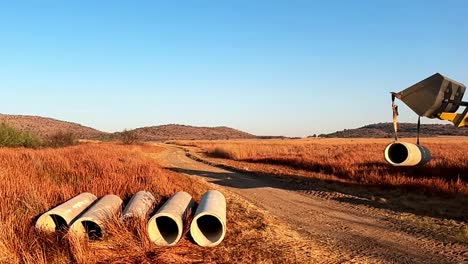 Front-end-loader-offloading-concrete-construction-water-pipes-on-a-rural-construction-site