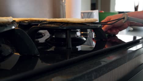 A-close-up-image-of-a-gas-stove-with-a-blue-flame,-used-for-cooking