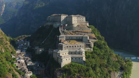 Fuerte-Bard-En-El-Valle-De-Aosta,-Italia,-Rodeado-De-Exuberantes-Colinas-Verdes,-Vista-Aérea