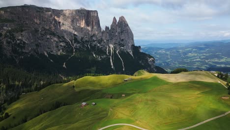 Schöne-Grüne-Alm-In-Den-Bergen-Mit-Blauem-Himmel,-Grünen-Bäumen-Und-Einem-Großen-Berg-Im-Hintergrund,-Dolomiten,-Italien,-Europa,-Drohne