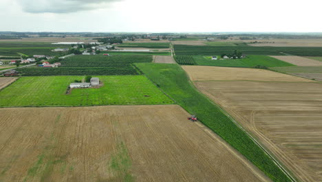 Aerial-shot-of-a-red-combine-harvester-with-trailers-in-a-wheat-field,-ready-for-loading