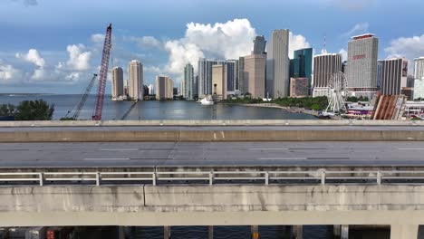 Aerial-lateral-shot-of-cars-on-bridge-in-front-of-Miami-Skyline-in-USA