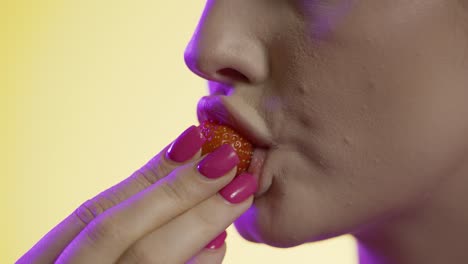 Woman-eating-a-strawberry-seductively,-mouth-close-up-detail