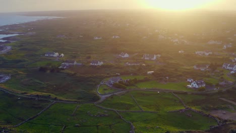 Aerial-view-of-Spiddal-and-Inverin-in-Connemara,-beautifully-backlit-by-a-stunning-sunset