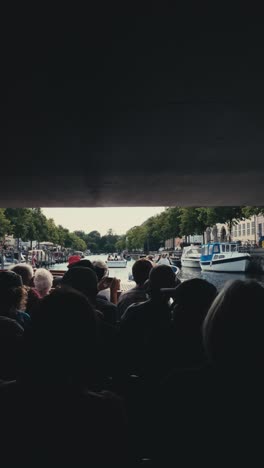 Vertical-view-of-tourists-on-a-boat-canal-tour-passing-under-a-bridge-in-Copenhagen