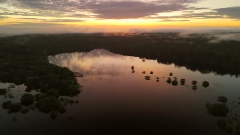 Eine-Drohne-Saust-über-Den-Amazonas-Dschungel-Und-Den-Fluss-Und-Fängt-Atemberaubende-Spiegelungen-Des-Sonnenuntergangs-Auf-Dem-Wasser-Ein,-Wodurch-Die-Lebendige-Schönheit-Des-Regenwaldes-Von-Oben-Hervorgehoben-Wird.