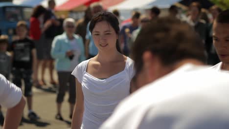 A-beautiful-and-happy-young-Asian-woman-in-a-white-t-shirt-dances-salsa-in-a-group-dance-at-an-outdoor-festival