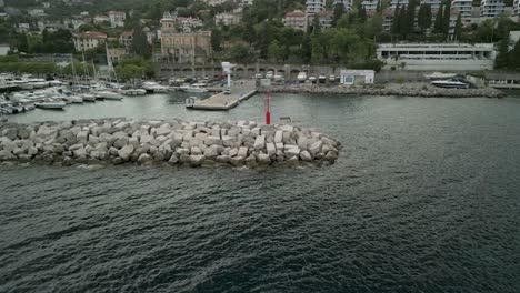 Marina-entrance-with-a-red-lighthouse-and-breakwater-seen-from-above-on-a-cloudy-day