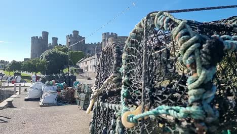 Crab-pots-stacked-on-Conwy-waterfront-revealing-idyllic-castle-overlooking-Wales-coastline