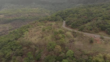 flying-towards-a-forested,-hilly-road