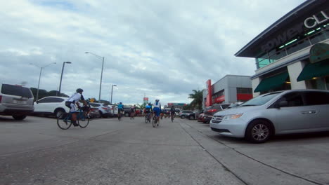 A-group-of-cyclists-ride-through-a-parking-lot-filled-with-cars