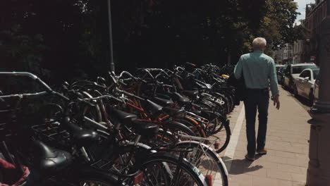 A-row-of-bikes-on-a-sidewalk-and-man-walking-in-Amsterdam