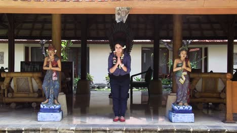 A-beautiful-girl-is-bowing-in-between-two-traditional-sculptures-in-bali