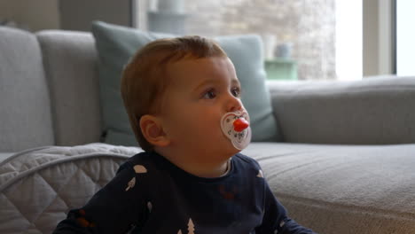 Primer-Plano-De-Un-Hermoso-Bebé-Con-Chupete-Mirando-Televisión-En-Un-Día-Lluvioso