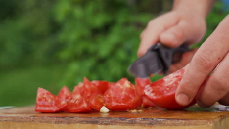 Side-view-of-male-hands-cutting-fresh-red-tomato-on-board-to-prepare-salad