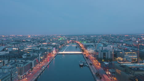 Aerial-view,-flying-up-the-Liffey-in-the-middle-of-Dublin-City-approaching-the-Same-Beckett-Bridge