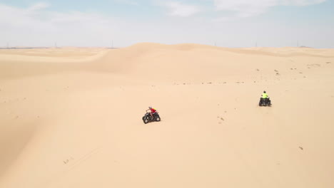 Slowmotion-aerial-drone-shot-of-friends-having-fun-in-the-desert-with-quadbikes-in-Abu-Dhabi,-UAE