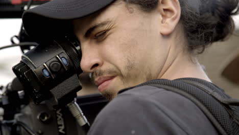 Primer-Plano-De-Un-Joven-Camarógrafo-En-Un-Equipo-De-Steadycam-Con-Cámara-Alexa-Mirando-A-Través-Del-Cristal-En-Una-Situación-De-Set-Al-Aire-Libre-Con-Luz-Natural