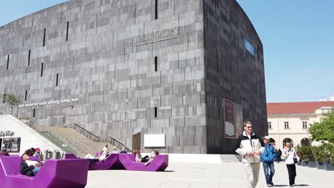 Running-Towards-The-Famous-Mumok-Art-Museum-In-Vienna-Austria-With-People-Roaming-And-Sitting-At-The-Violet-Seats-In-The-Pavilion---Time-Lapse