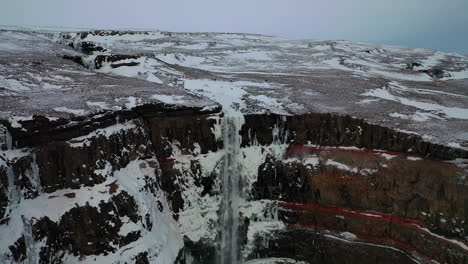 Hengifoss-Waterfall-Covered-In-White-Snow-In-East-Iceland---Winter-Landscape---aerial-drone-shot