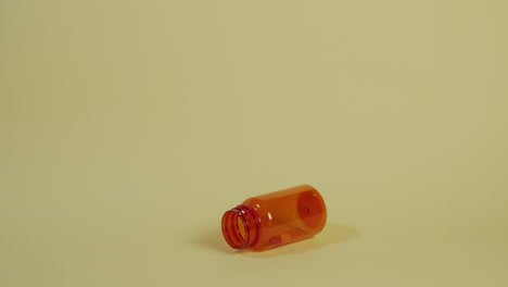 Slow-motion-wide-shot-of-a-pill-bottle-with-only-one-pill-as-it-falls-and-bounces