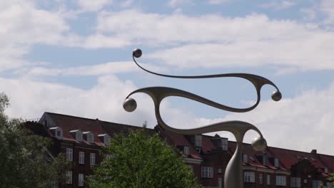 Spinning-statue-in-Moelleparken-in-Aarhus,-Denmark-on-a-hot-summers-day-with-sky-in-the-background