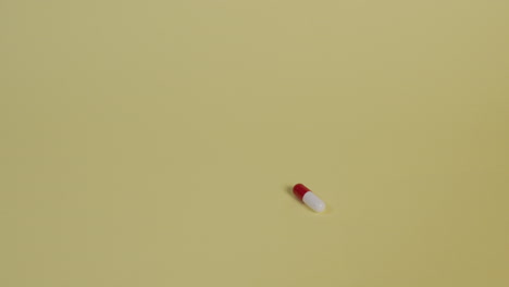 Slow-motion-high-angle-medium-shot-of-a-single-pill-as-it-falls-vertically-and-bounces